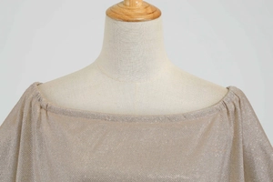 Detailed macro view of champagne off-shoulder dress with metallic shimmering knit fabric