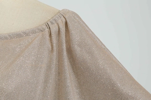 Detail of champagne gold metallic fabric with elegant shoulder pleats and shimmering texture