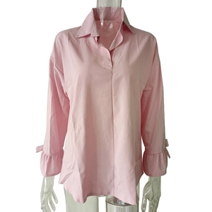 Detail of light pink blouse featuring ruffled trumpet sleeves and small bow accents