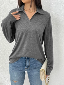 Détail d'un polo à manches longues gris foncé avec col en V et poche poitrine pratique