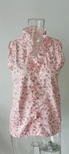Dettaglio del top rosa senza maniche con stampa floreale e balze decorative sullo scollo