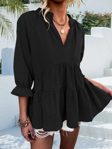 Detail of black V-neck babydoll top with pleated ruffled hem and textured fabric