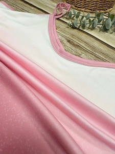 Pink and white summer camisole dress with spaghetti straps on a natural wood surface