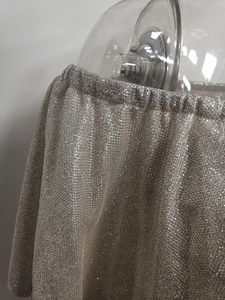 Close-up of silver sequin fabric with metallic shimmer and elasticated waist detail