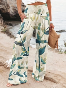 Detail of high-waisted smocked waistband and leaf print on bohemian wide-leg trousers