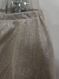 Macro detail of glittering metallic mesh fabric on this shimmering off-shoulder evening gown