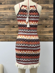 Dettaglio dell'abito in maglia boho con motivi geometrici a onde e nappe a frange