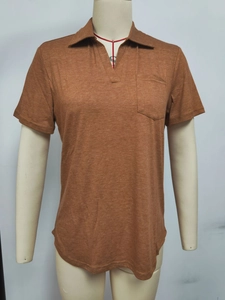 Détail d'un polo marron caramel avec col en V, poche poitrine et texture en maille
