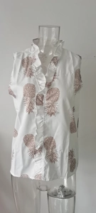 Detail of white sleeveless shirt featuring ruffles and brown pineapple print patterns