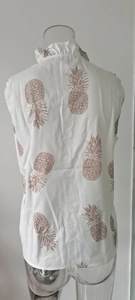 Detail of white sleeveless blouse with brown pineapple print and ruffled collar back