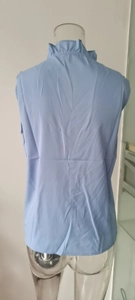 Detail view of the ruffle stand collar and back design on a light blue sleeveless blouse