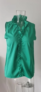 Detail of vibrant green sleeveless blouse featuring ruffled trim and a mock neckline
