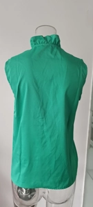Detail of emerald green sleeveless ruffled high collar blouse with pleated texture fabric