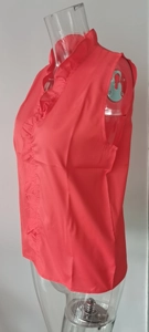 Detail view of red sleeveless blouse with ruffle trim and soft pleats on a mannequin