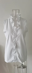 Detail view of the standing collar and dense ruffles on this white sleeveless blouse
