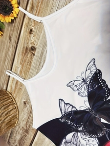 Detail of white summer dress featuring butterfly print on smooth elastic fabric