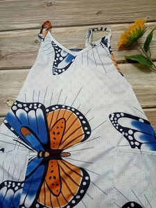Detailed view of white floral camisole with colorful butterfly print on wood texture
