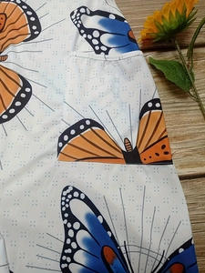 Detail shot of summer jumpsuit featuring floral butterfly print and functional patch pocket