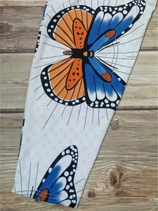 Detail of vibrant butterfly prints on white fabric over a rustic wooden background