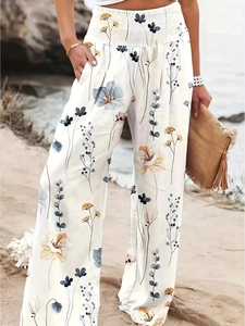 Detail of high-waisted smocked waistband on floral bohemian wide-leg trousers for women