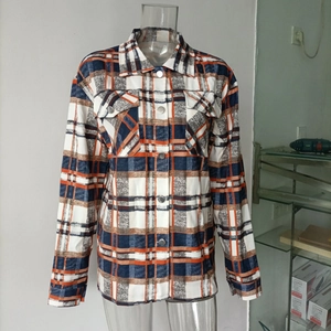 Detail of orange and blue plaid flannel shirt jacket with metal buttons and flap pockets