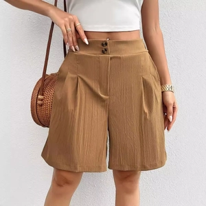 Detail of high waisted caramel shorts featuring double button closure and pleated design