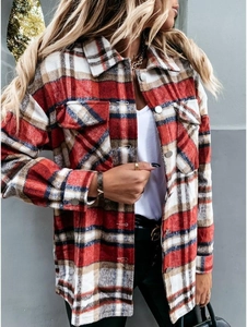 Detail of red plaid shacket featuring chest pockets and silver buttons on flannel fabric
