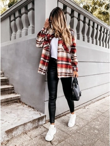 Detail shot of a women's red and white plaid flannel shirt with black leather leggings