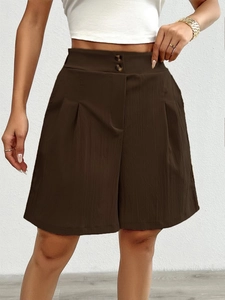 Detail of dark brown high-waisted shorts with double buttons and pleated design