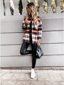 Outdoor street shot of a long-sleeved plaid shacket with black slim-fit trousers