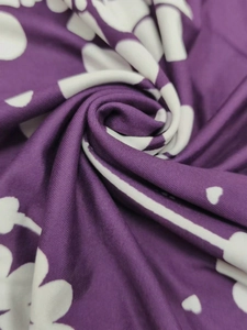 Gros plan du tissu violet avec motifs trèfle blanc montrant la texture douce de la robe
