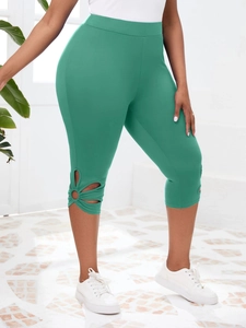 Détail de legging capri vert foncé avec découpes stylées sur les côtés inférieurs des jambes