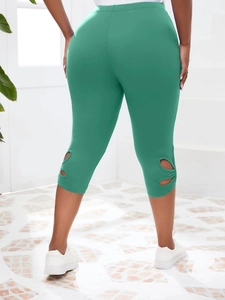 Détail des découpes ajourées en forme de fleurs sur l'ourlet du legging capri vert taille haute