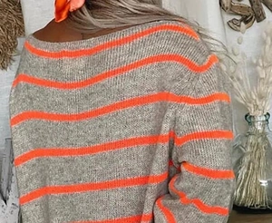 Dettaglio di un maglione grigio a righe arancioni con texture in maglia morbida
