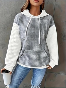 Detail view of grey and white patchwork hoodie featuring unique quilted textured fabric