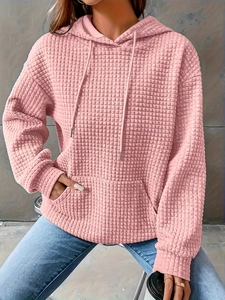 Detail of light pink hoodie showing waffle texture fabric, drawstring hood, and kangaroo pocket