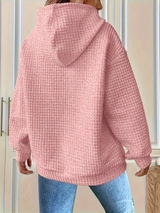 Detail of light pink hoodie showing waffle texture fabric and relaxed hooded design from behind