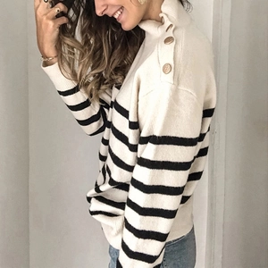 Dettaglio dei bottoni dorati sulla spalla e collo alto del maglione a righe