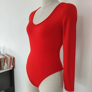 Detail of red ribbed long sleeve bodysuit featuring a deep V-neck and tight knit texture