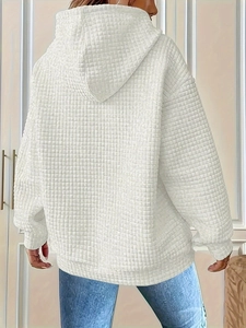 Close-up of white oversized hoodie featuring distinctive waffle texture and cozy hood
