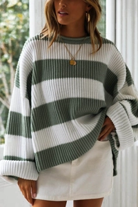 Detail of green and white striped oversized knit sweater with rolled cuffs and texture