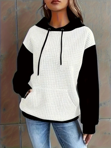 Detail of color-block hoodie with quilted texture, black drawstrings and kangaroo pocket