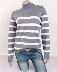 Dettaglio del maglione a righe con collo alto e bottoni metallici sulla spalla