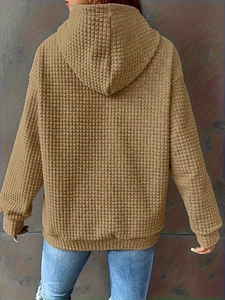 Detail view of brown hoodie featuring waffle texture fabric and relaxed drop shoulder design