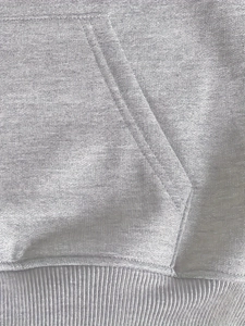Detailaufnahme grauer Kapuzenpullover mit Fokus auf Kängurutasche und Rippbündchen am Saum