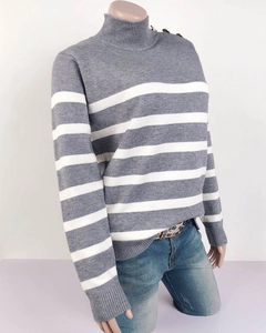 Dettaglio del maglione a righe grigie con bottoni decorativi sulla spalla e collo alto