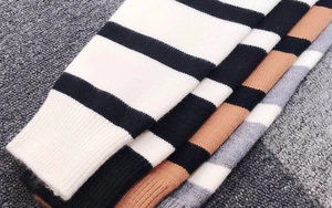 Dettaglio dei polsini in maglia a coste a righe nei colori nero, marrone e grigio