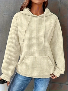 Detail of beige waffle textured hoodie showing thick quilted fabric and front kangaroo pocket