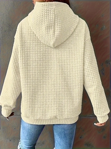 Back view of beige oversized hoodie featuring waffle knit texture and ribbed cuffs