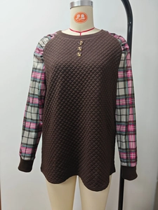 Dettaglio della trama a rombi trapuntati e maniche patchwork a quadri sul maglione